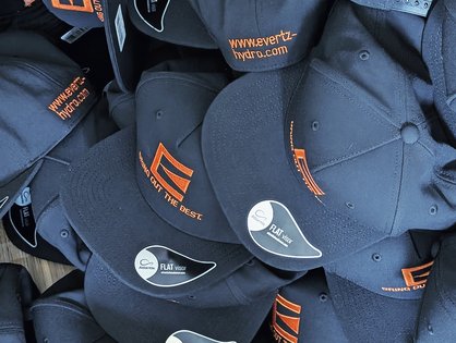 Bestickte Flat Caps mit orangefarbenem Logo und Schriftz&uuml;gen f&uuml;r Evertz aus Betzdorf